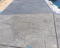 alt="grey stamped concrete pool deck installation"